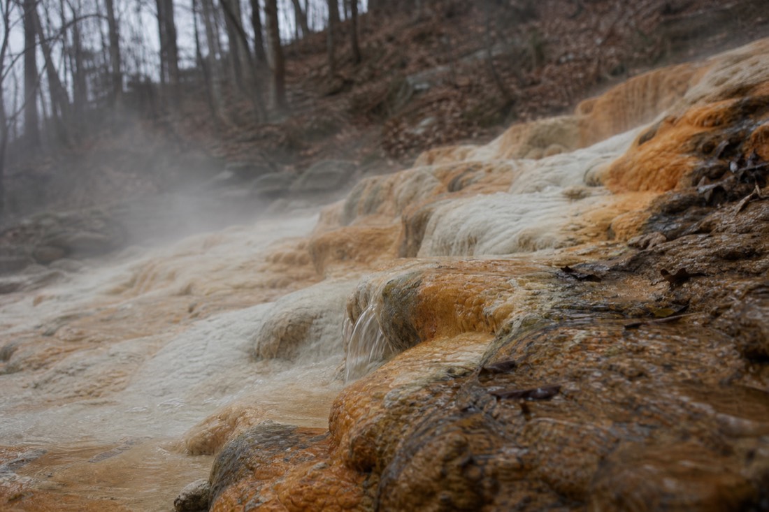 Mineral-streaked thermal spring water flowing over rocks at the foot of the Buda hills