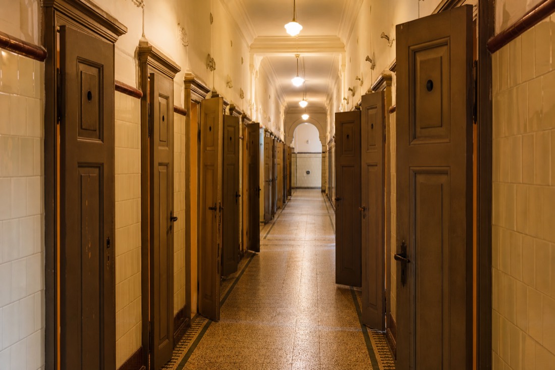 Row of numbered wooden changing cabins along a tiled corridor inside a Budapest thermal bath, empty and softly lit