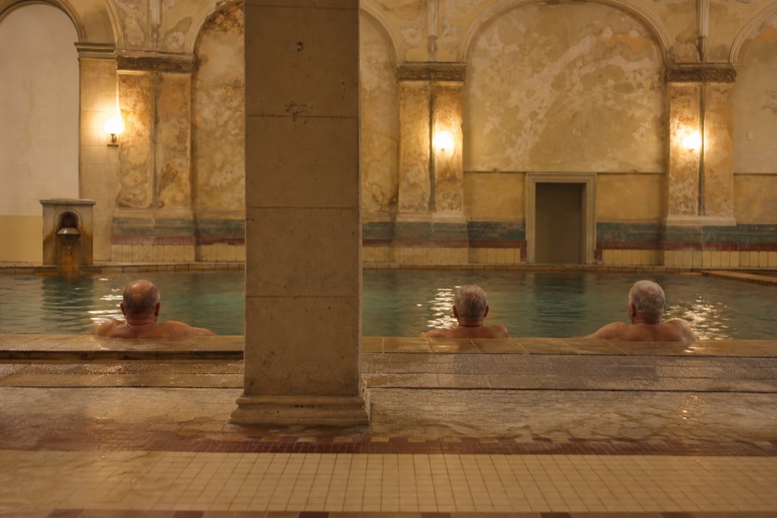 Quiet warm pool with a few older bathers relaxing at an unpolished local thermal bath in Budapest