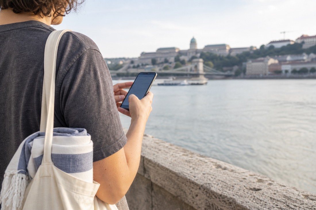 Traveller planning a spa day on a phone beside the Danube in Budapest
