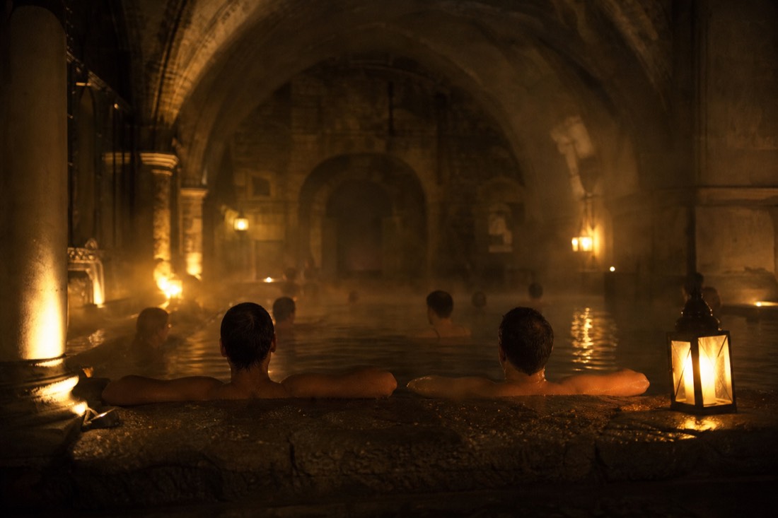 Bathers relaxing in a dimly lit historic thermal pool at night in Budapest