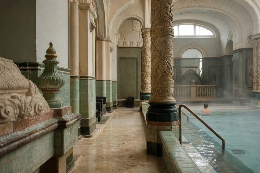 Indoor medicinal pool hall with columns and still warm water at a historic Budapest bath