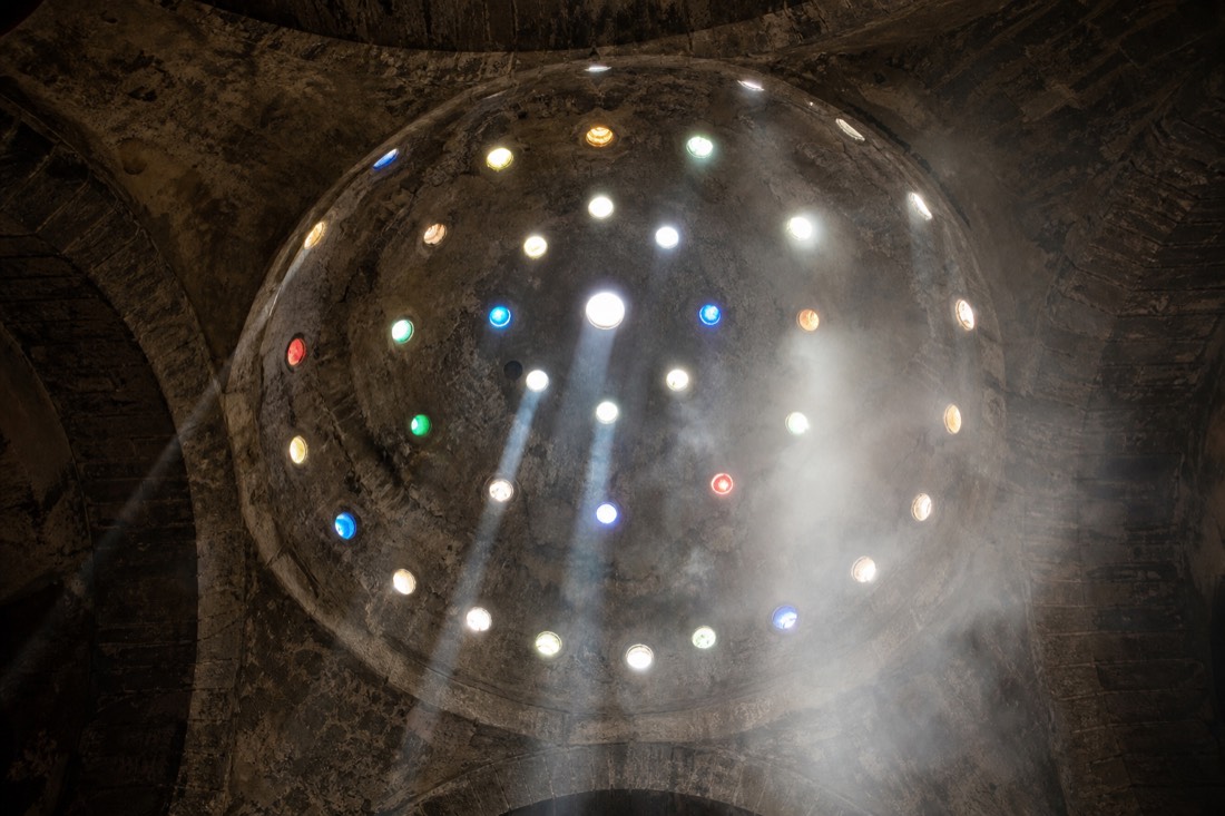 Stone cupola with hexagonal glass openings above a thermal pool in a Budapest Turkish bath