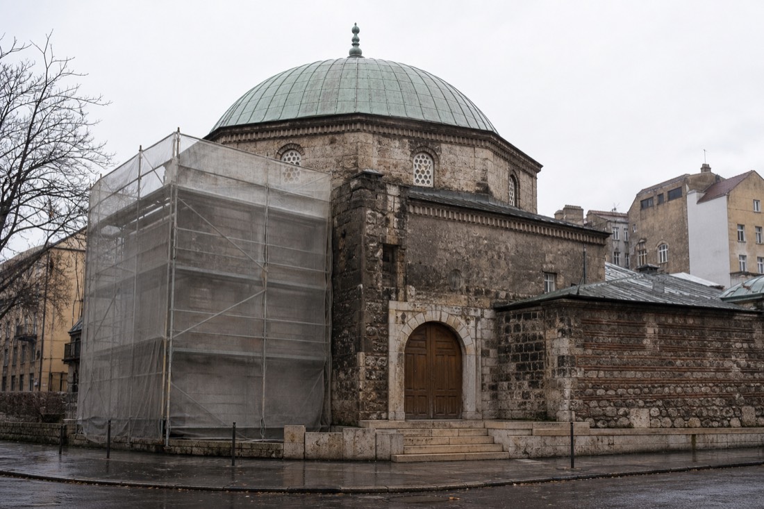 Weathered domed roof of a closed 16th-century Turkish bath building behind scaffolding in Budapest