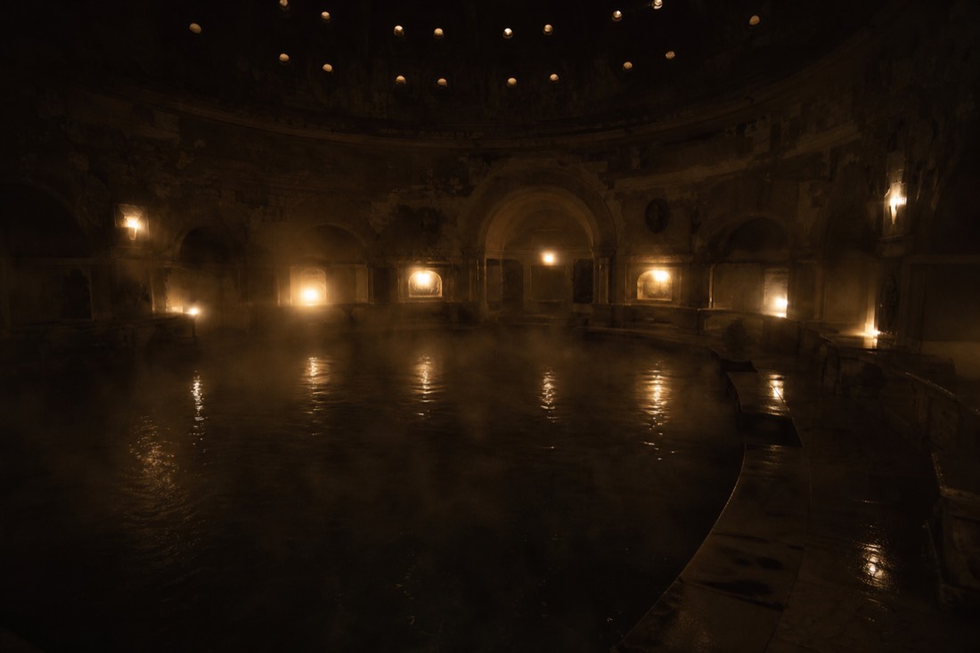 Steam drifting over a dim thermal pool during a late night bathing session in a Budapest Turkish bath