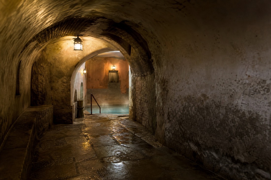 Arched stone passage leading to a warm pool inside an old Ottoman bath house in Buda