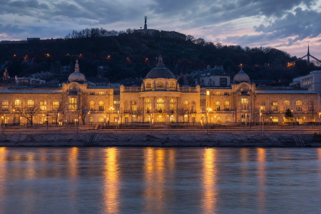 Two contrasting Budapest bath scenes, a quiet domed pool and a grand riverside bath facade at dusk