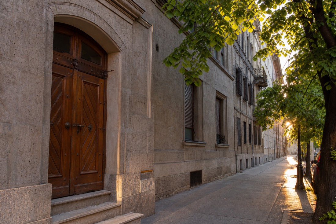 Understated stone entrance of a historic bath house on a quiet Buda street in early morning light