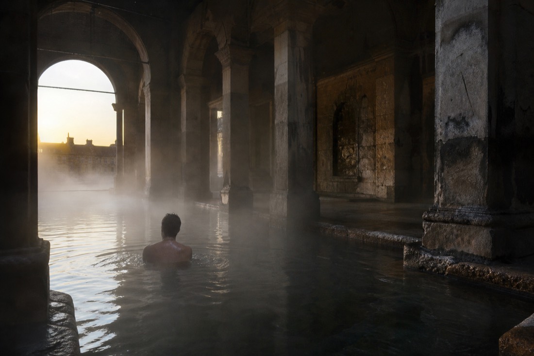 Early morning steam drifting over warm water in a nearly empty historic thermal bath
